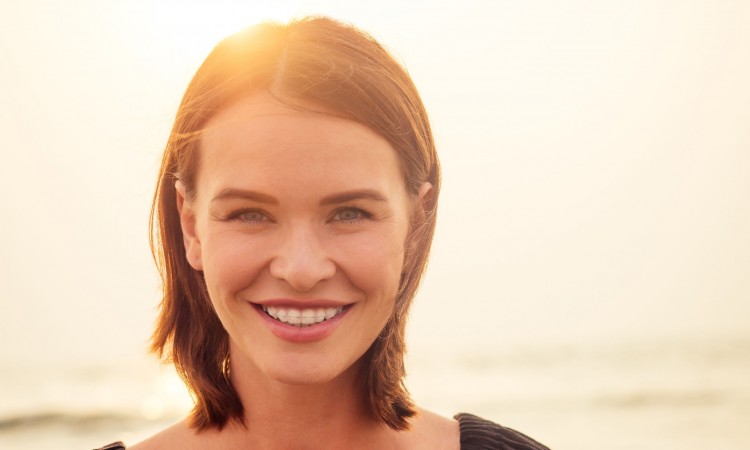 woman, 30-35 years old smiling toothy smile with braces on sea ocean beach background.spf and sunscreen.