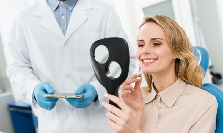 Woman choosing tooth implant looking at mirror in modern dental clinic