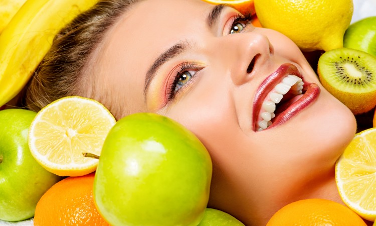 Close-up portrait of a beautiful smiling woman among fresh fruts. Healthy eating, juice. Make-up, cosmetics. Healthy teeth.