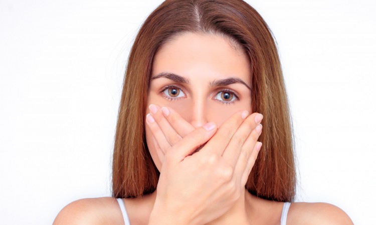 Beautiful woman closes her mouth with her hands